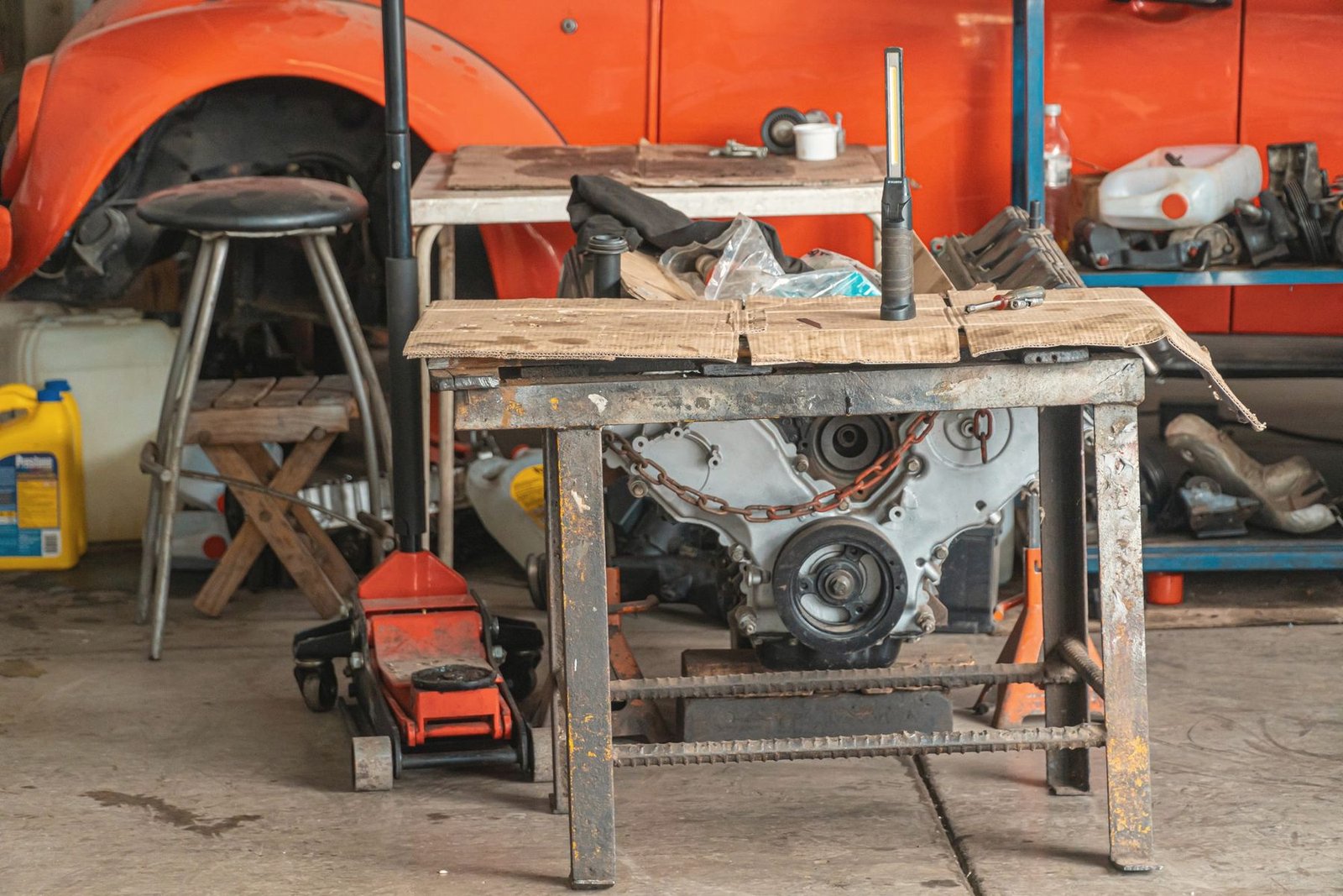 An engine sitting on a shop table with a floor jack nearby